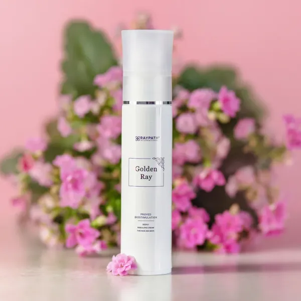 Krem Golden Ray Raypath 50 ml na tle różowych kwiatów